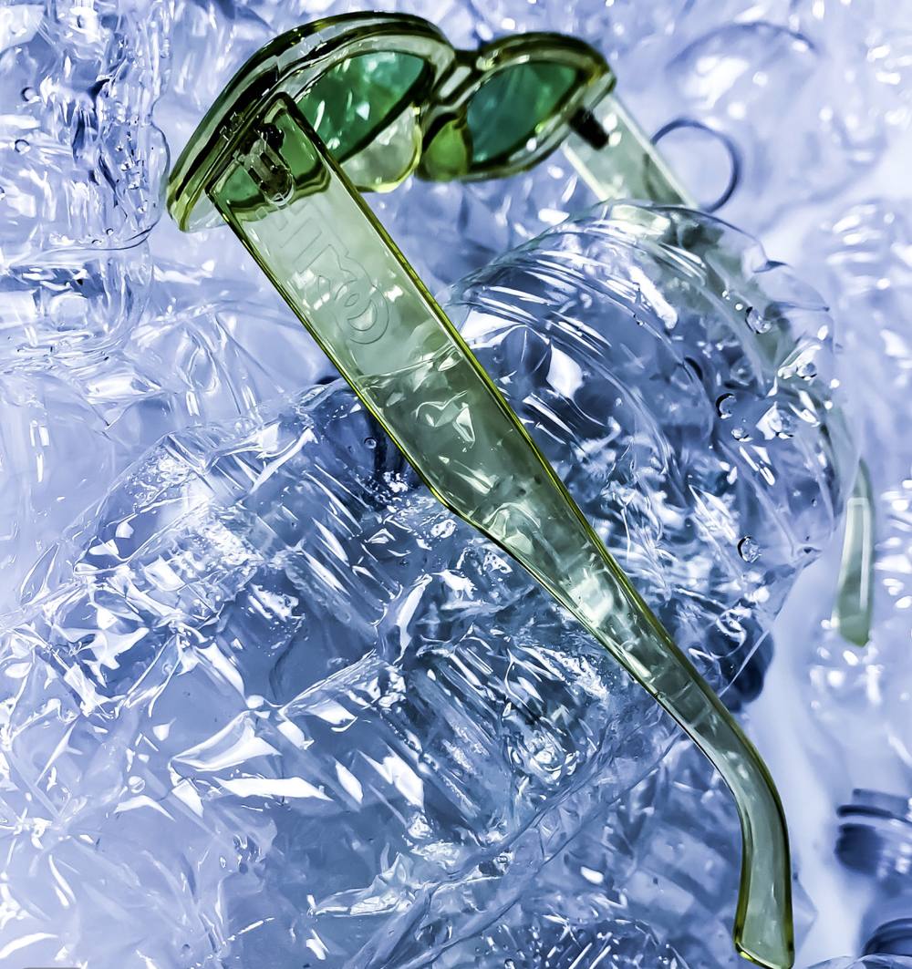 Green translucent sunglasses on crushed plastic bottles