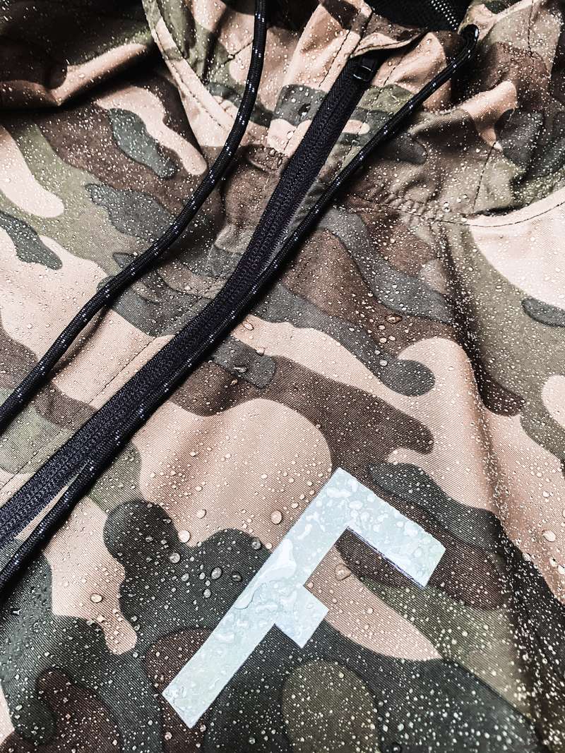 Camo jacket with reflective chest mark, covered in water droplets